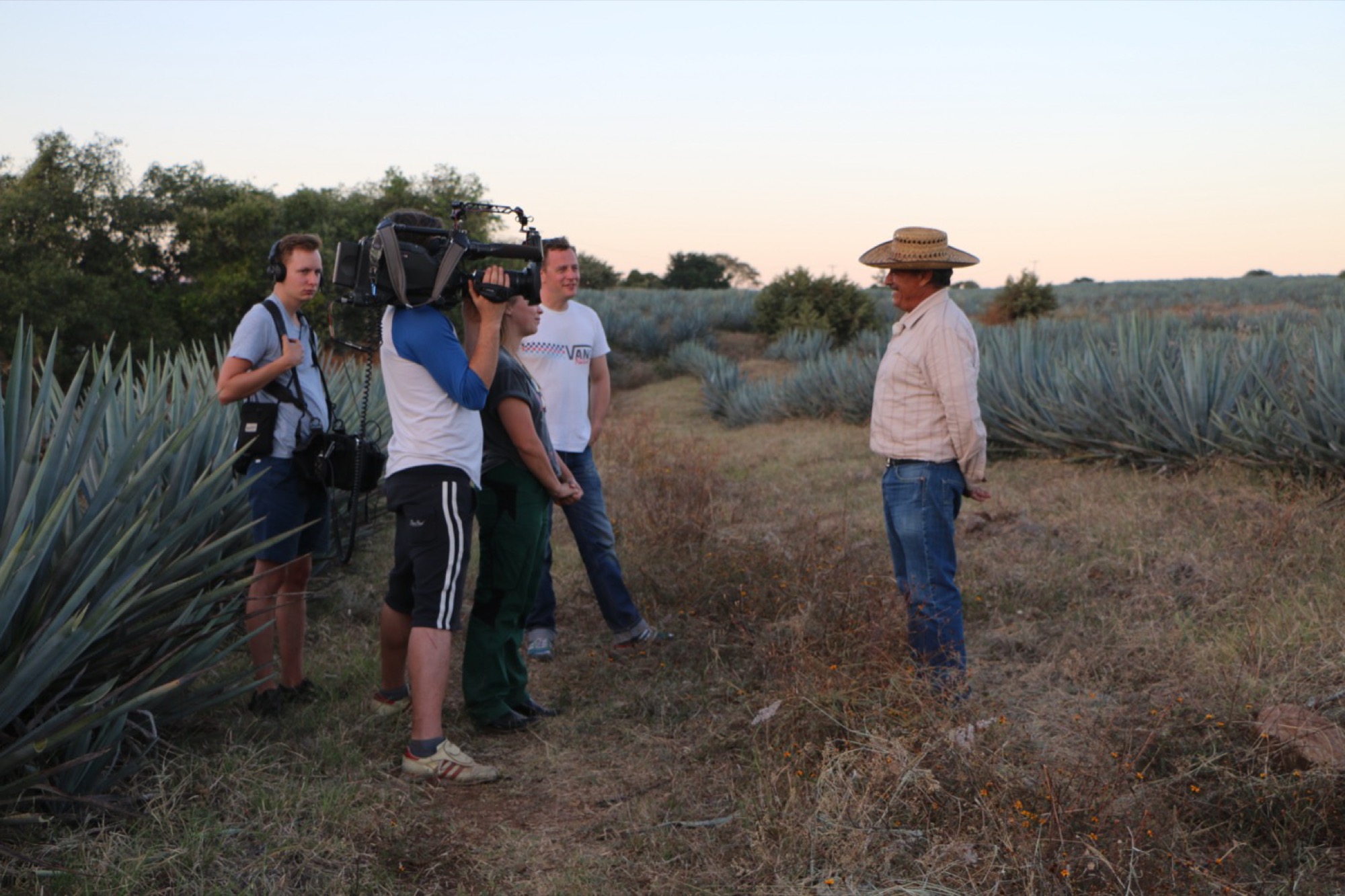 Crew filming with local workers in an agave field