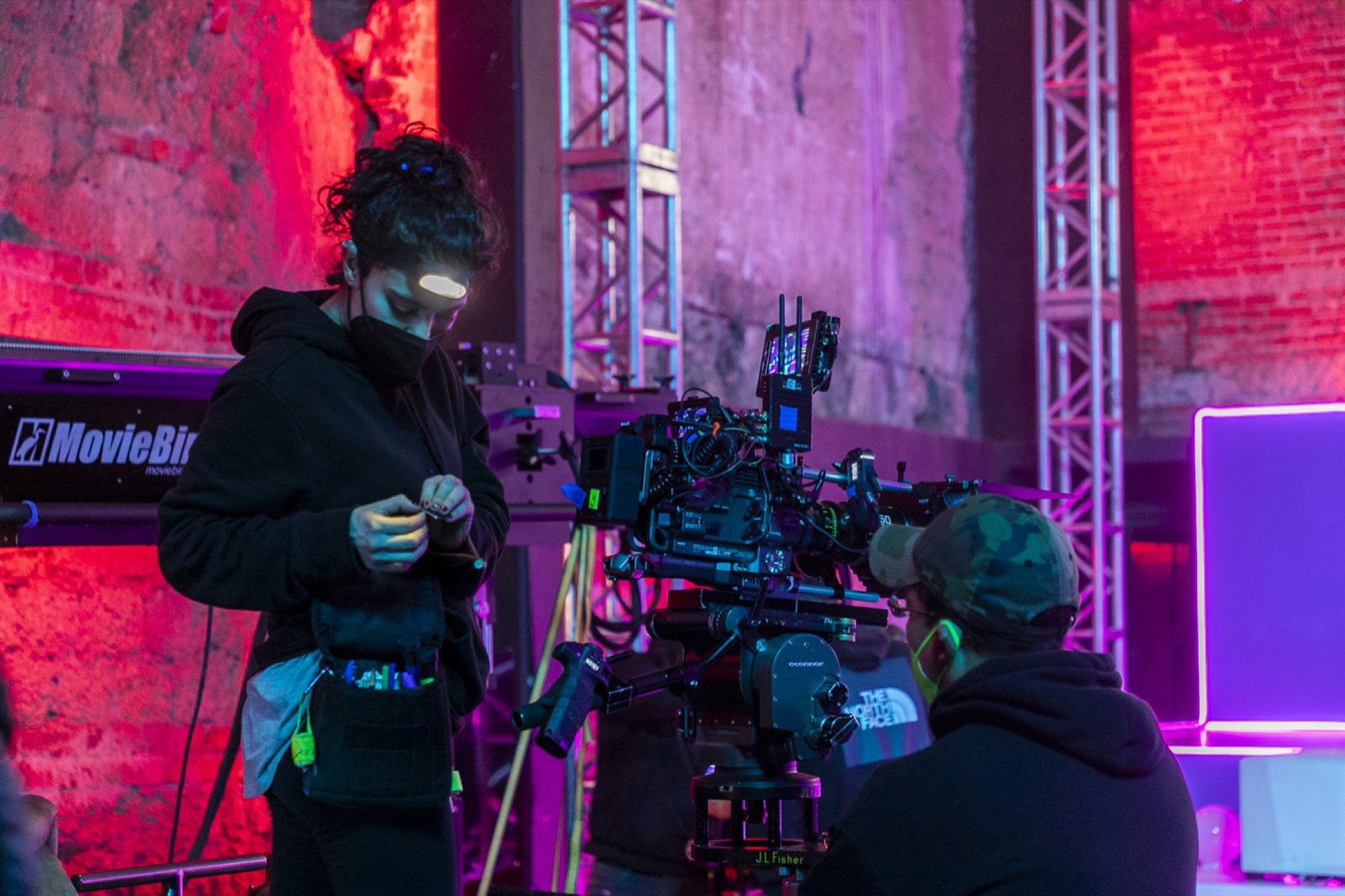 Camera operator rigging a crane on a lit studio set