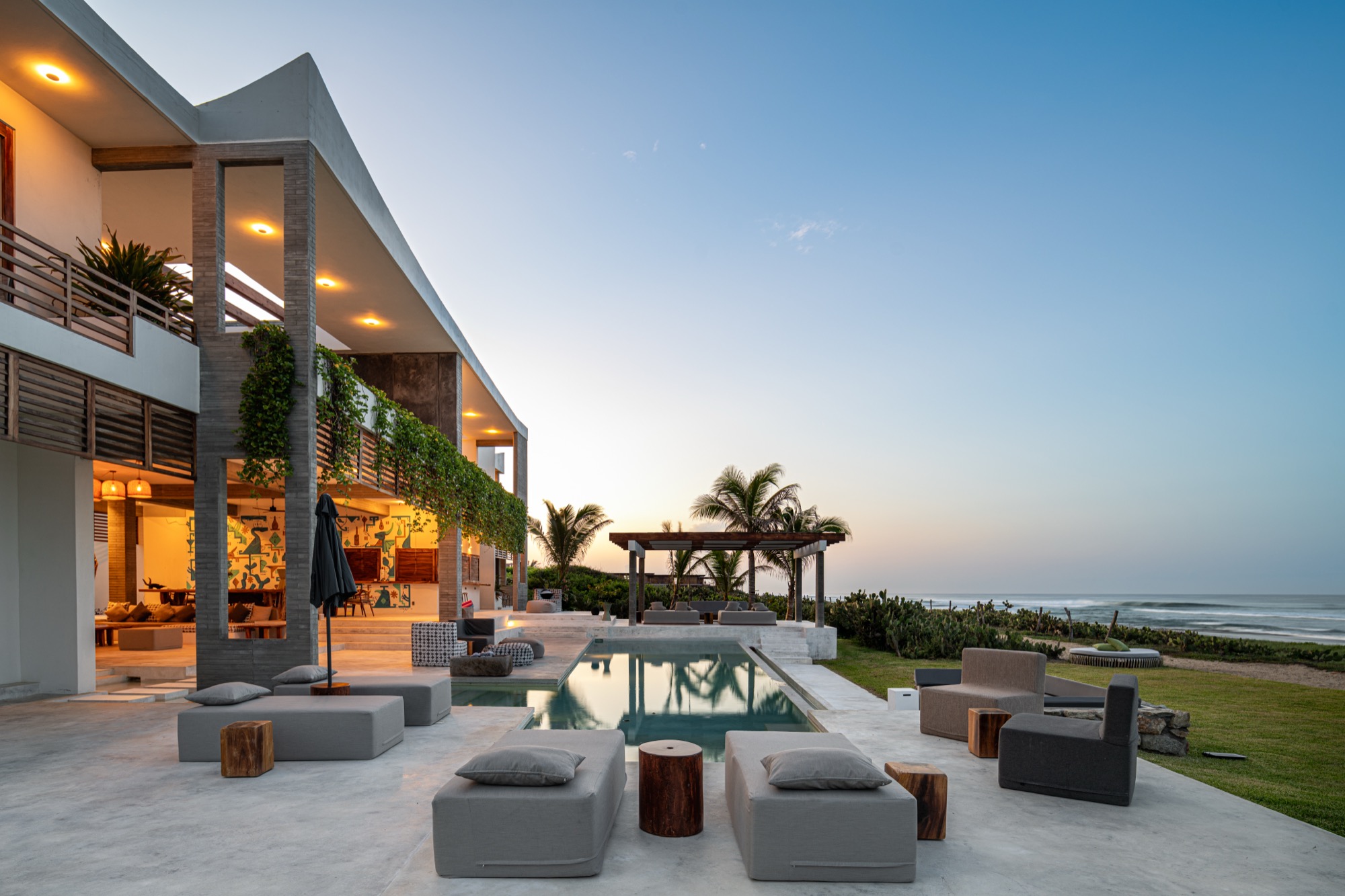 Beachfront villa terrace at dusk with pool and lounge seating, illustrative example